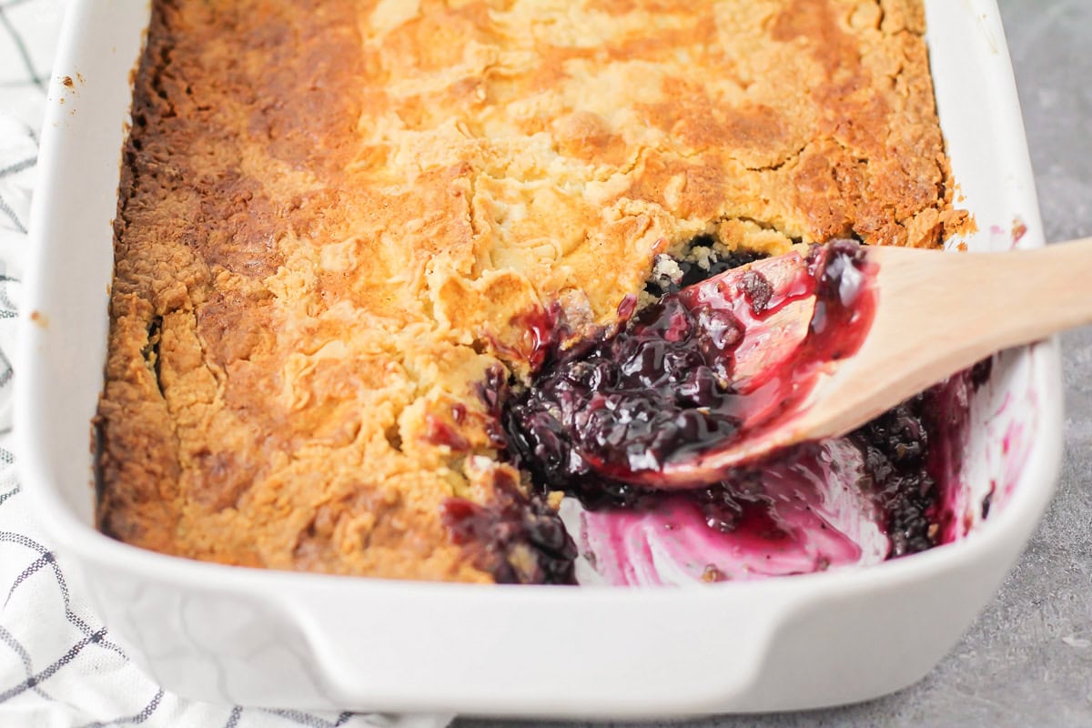 Wooden scoop in a homemade blueberry dump cake recipe.