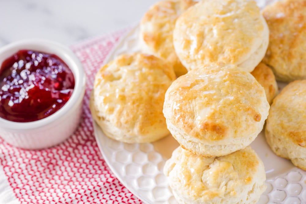 Buttermilk biscuits stacked on a plate with a side of jam