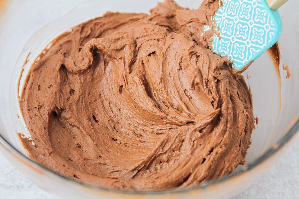 Chocolate buttercream frosting whipped in a glass bowl.