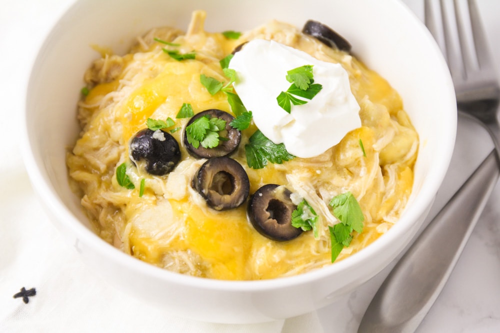 Slow cooker chicken enchiladas dished into white bowl.