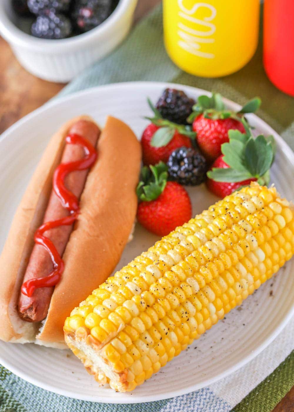 Microwave corn on the cob served with a hot dog and fruit