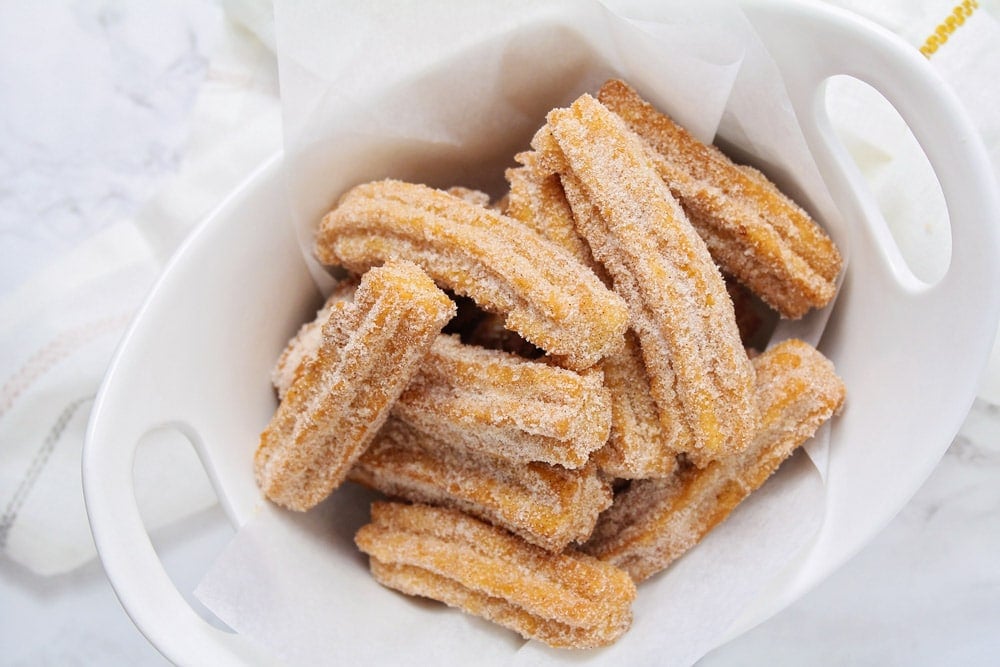 Disney Recipes - Several churros in a white serving bowl.