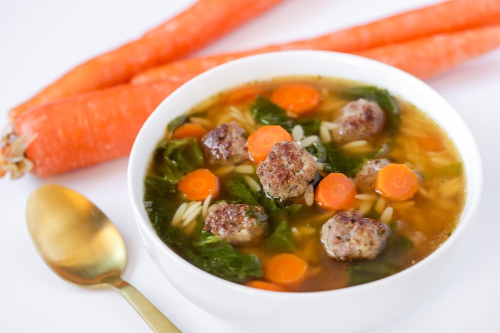 Italian Soups - White bowl of italian wedding soup served with a golden spoon.
