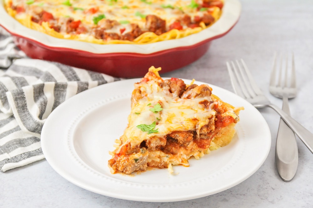 Slice of spaghetti pie on white plate.