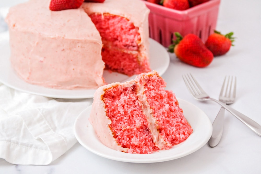 A slice of strawberry cake on a white plate.