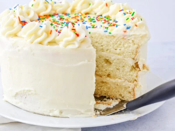 Homemade Vanilla cake with a slice missing on cake stand.