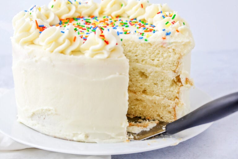 Homemade Vanilla cake with a slice missing on cake stand.
