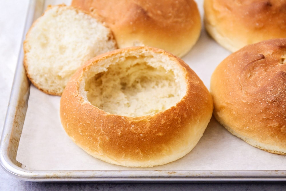 A lined baking sheet of bread bowls.