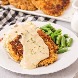 Chicken fried steak topped with gravy and served with green beans.