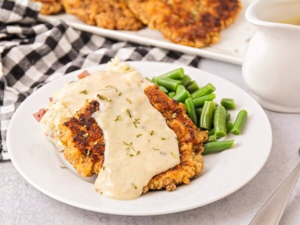 Chicken fried steak recipe topped with gravy and served with green beans.