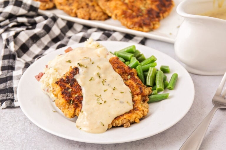 Chicken fried steak recipe topped with gravy and served with green beans.
