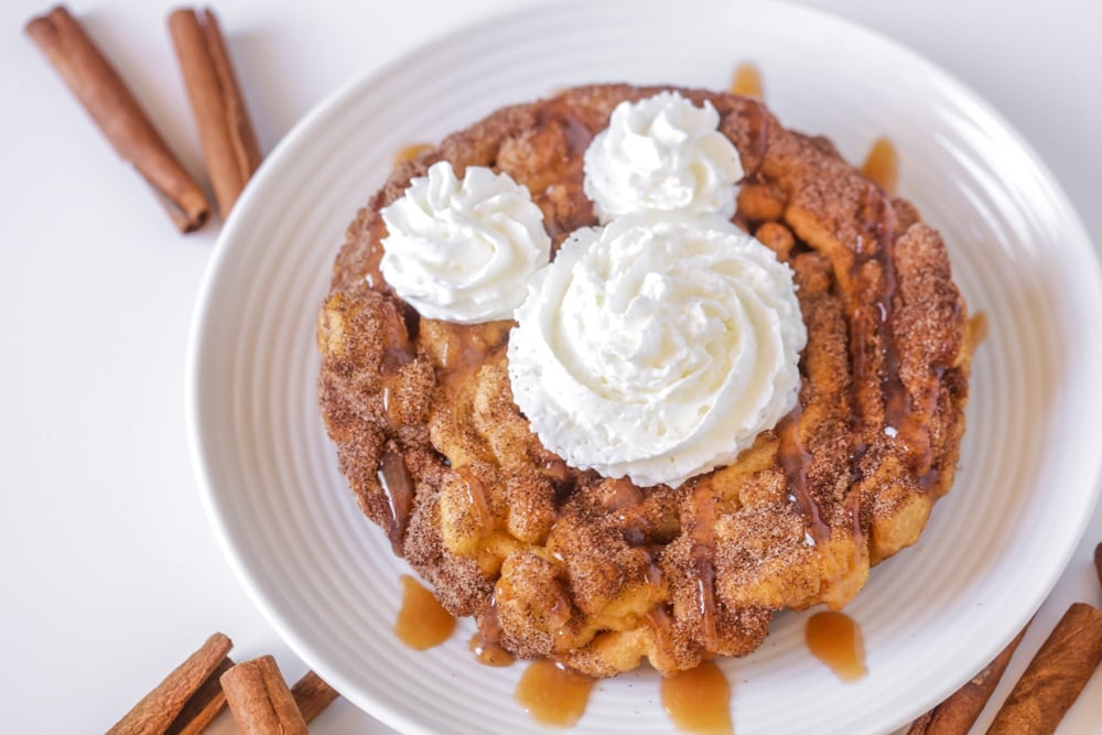 Churro funnel cake topped with caramel and whipped cream