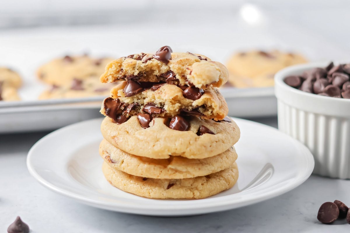 Eggless chocolate chip cookies stacked on top of each other on white plate.