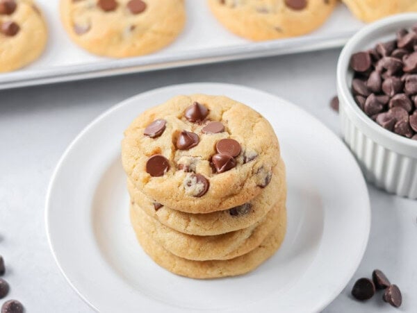 Eggless chocolate chip cookies stacked on each other on white plate.