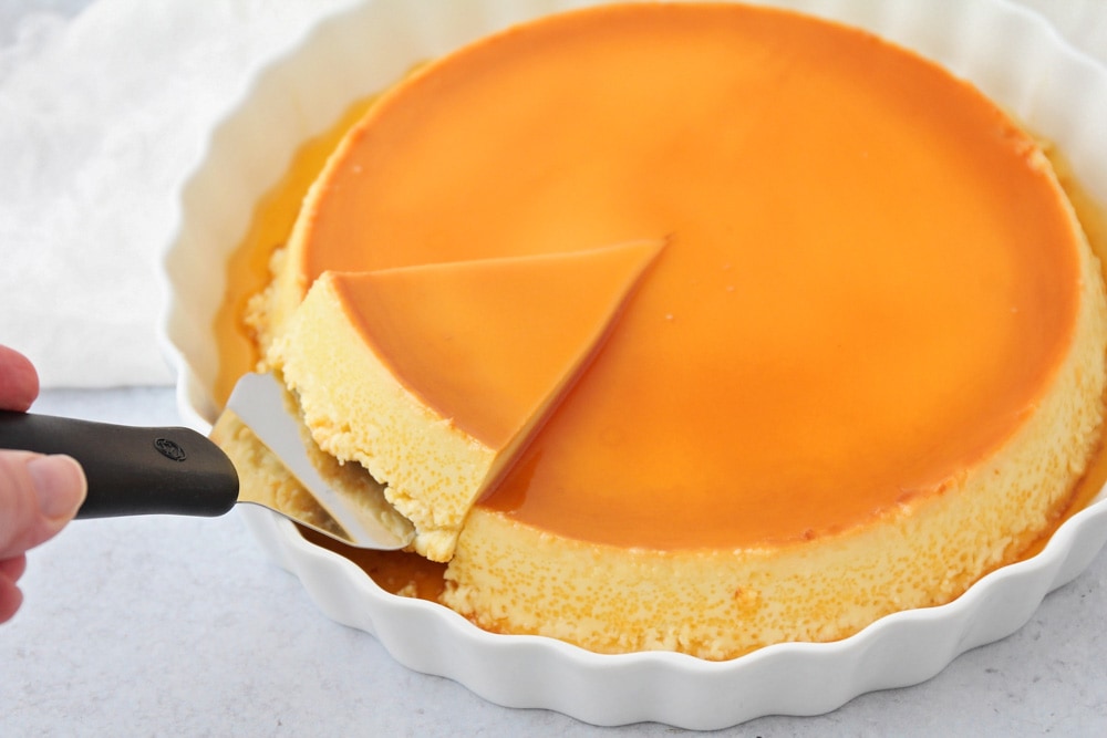 A slice of flan being cut with a serving utensil.