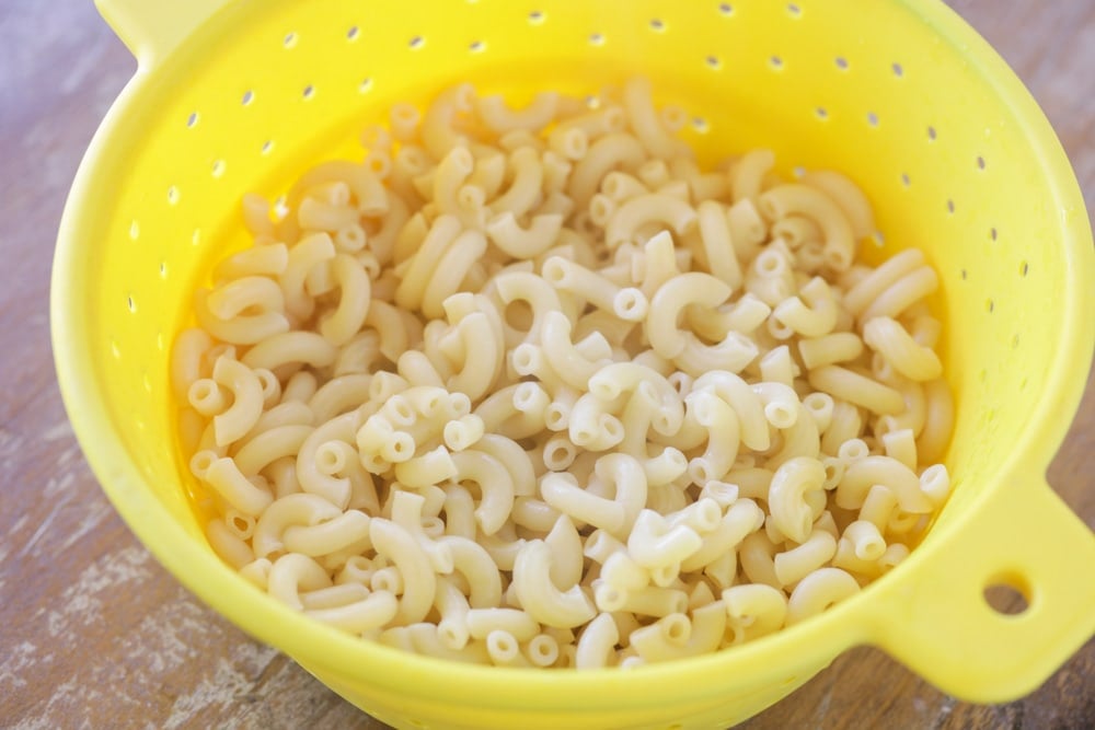 Cooked macaroni noodles in a yellow colander.