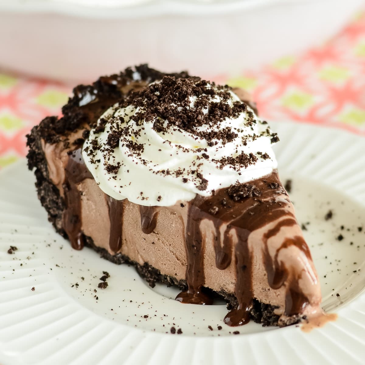 Mud pie recipe sliced and served on a white plate with wipped cream.
