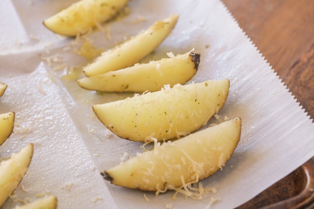 Homemade potato wedges topped with parmesan before being baked
