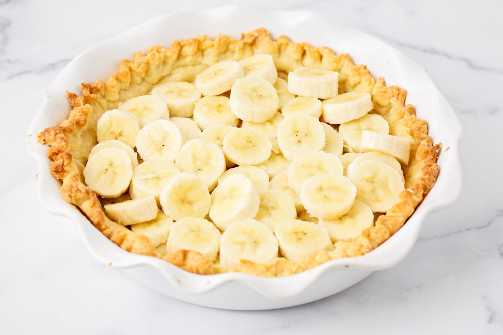 Layering bananas on the pie crust for homemade banana cream pie.