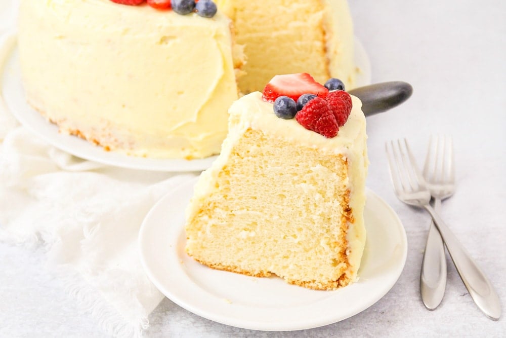 A slice of chiffon cake on a white plate topped with berries.