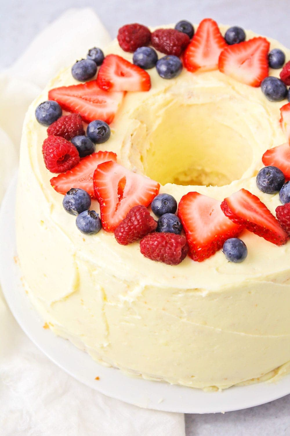 Easy chiffon cake recipe topped with orange frosting and fresh berries.