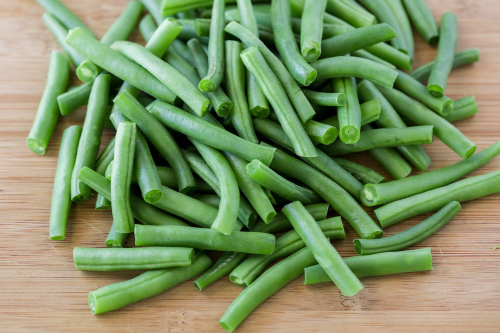 Fresh green beans on a wooden cutting board. 