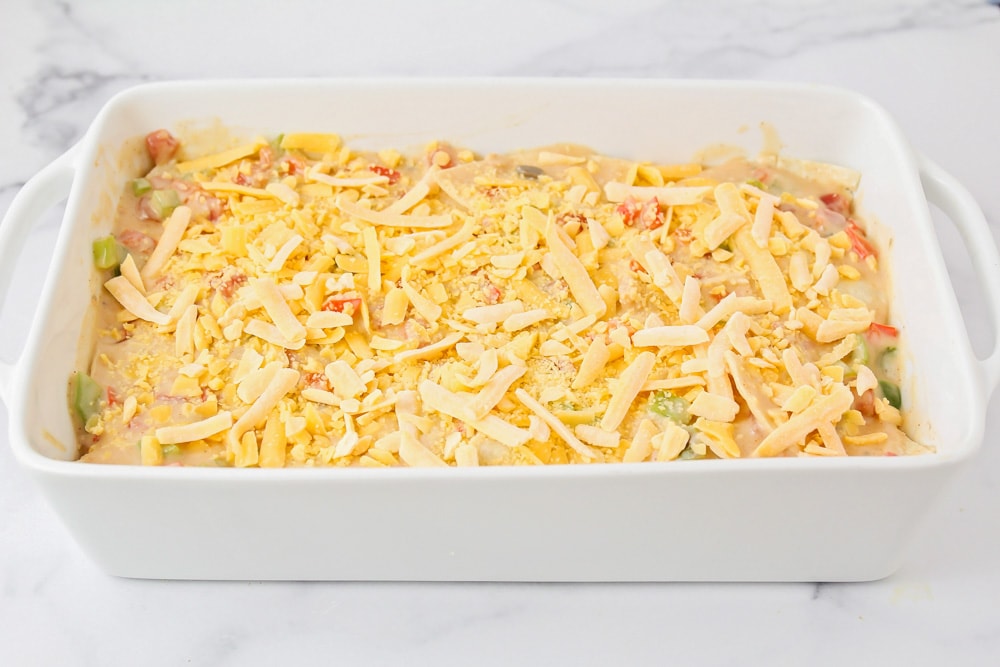 King Ranch chicken casserole topped with cheese and ready to bake.