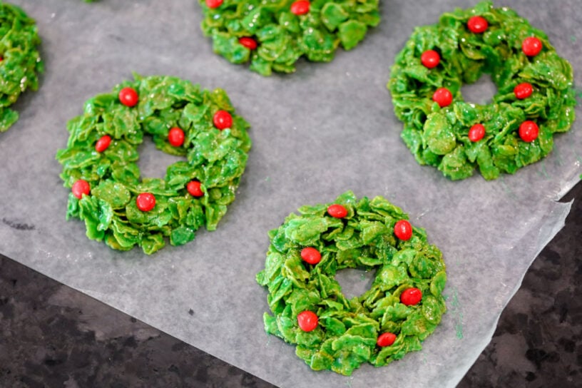 Cornflake Christmas wreath cookies cooling on wax paper.