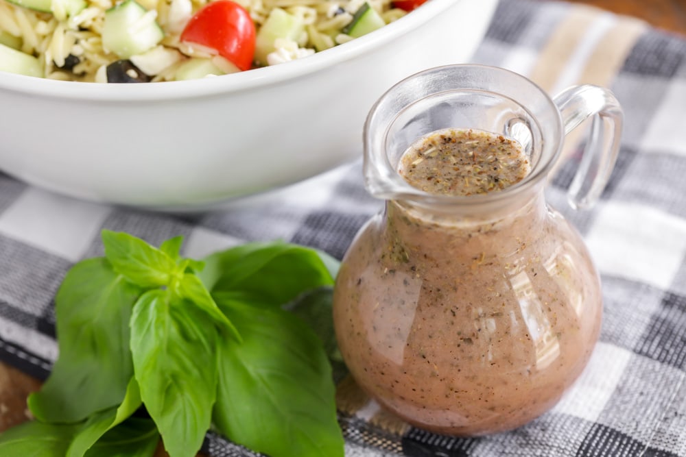 Greek salad dressing in a clear dressing carafe.