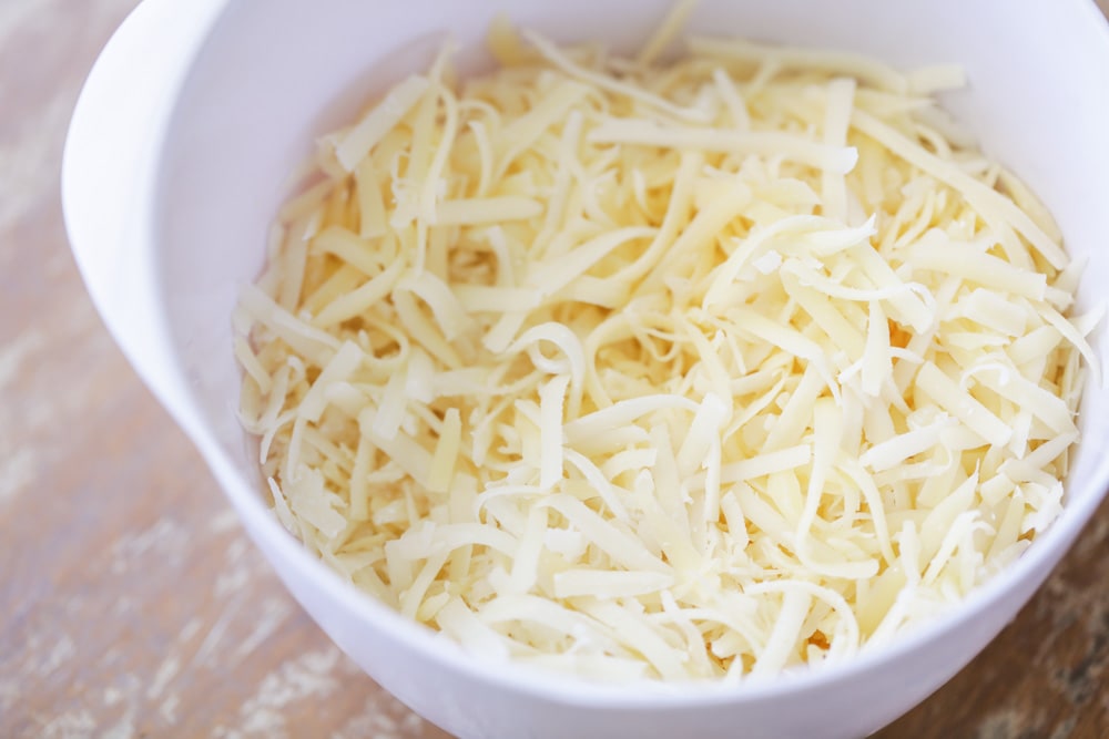 Cheeses combined in a bowl for cheese fondue recipe.