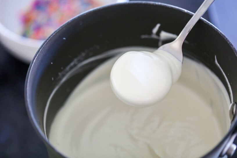 An Oreo being dipped in white chocolate.