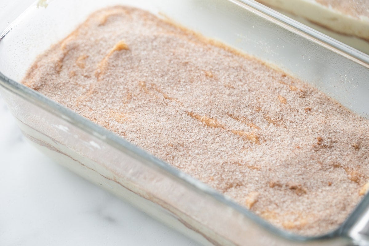Dough and cinnamon and sugar mixture layers in a glass loaf pan