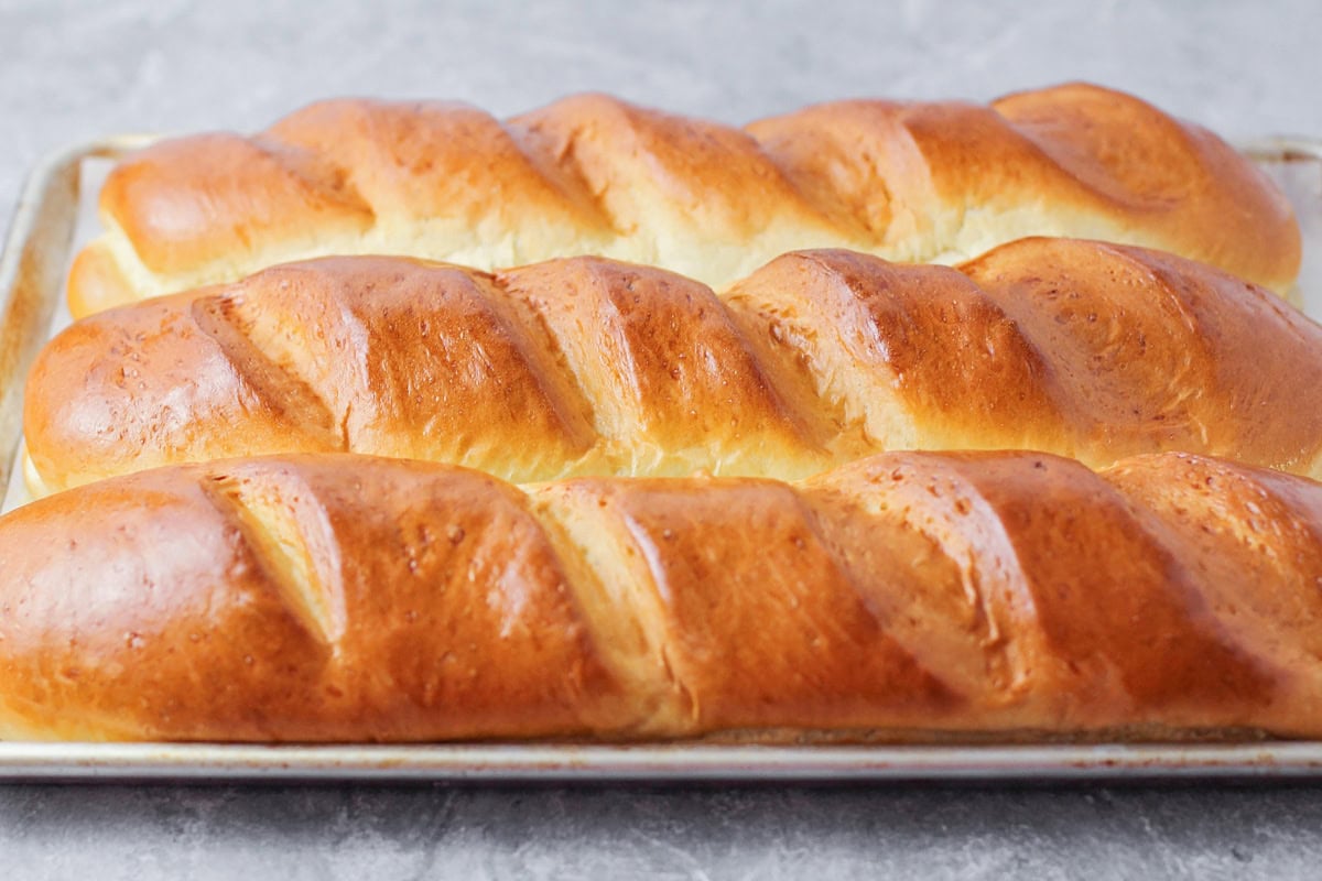 Three loaves of french bread on a sheet pan.