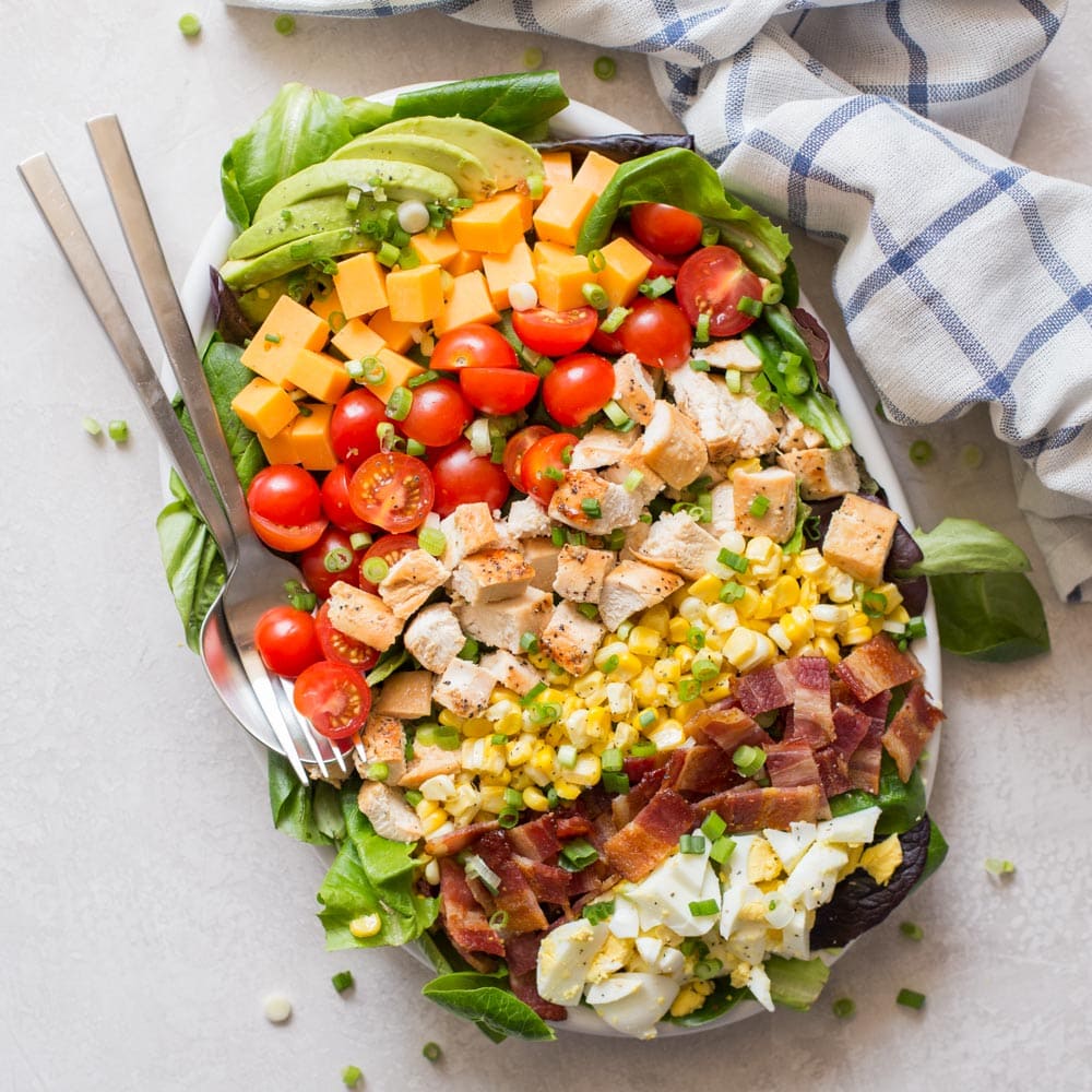 Green Salad Recipes - Cobb salad in a white serving platter with a fork and spoon. 