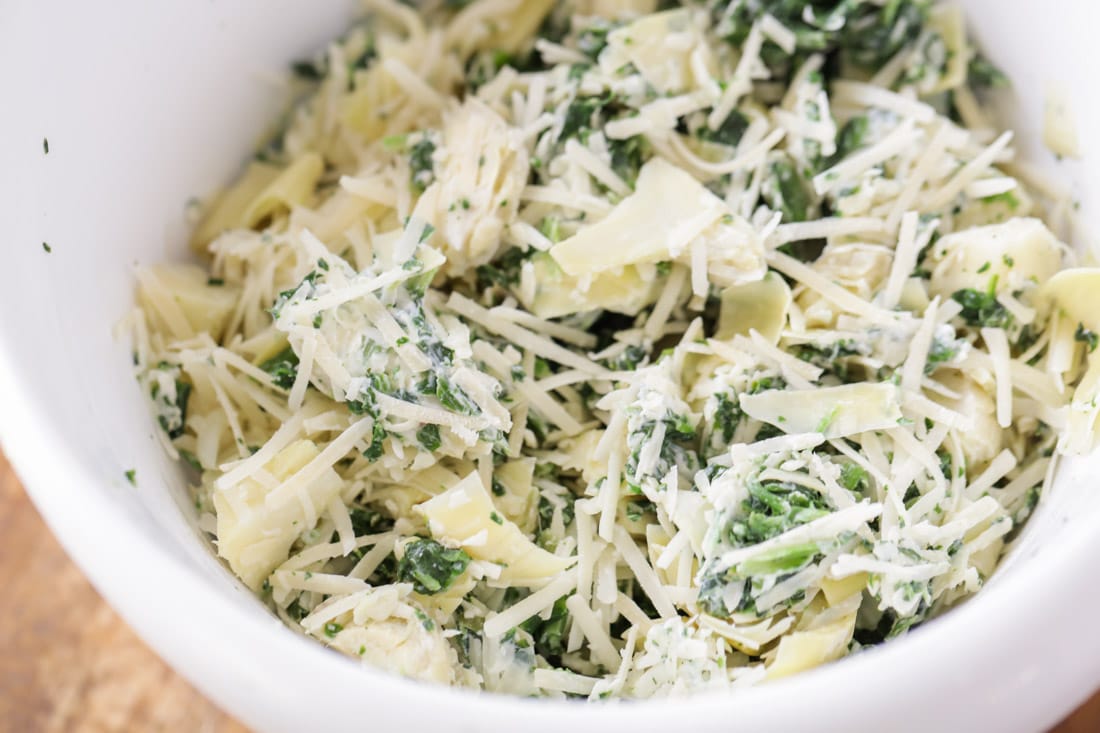 Combining ingredients in a bowl for spinach artichoke dip