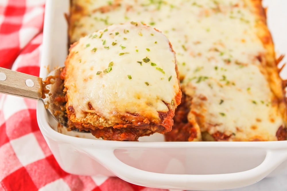 Serving a slice of easy eggplant parmesan with a spatula.