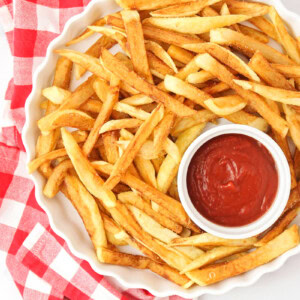 Homemade French fries in a dish with ketchup on the side.