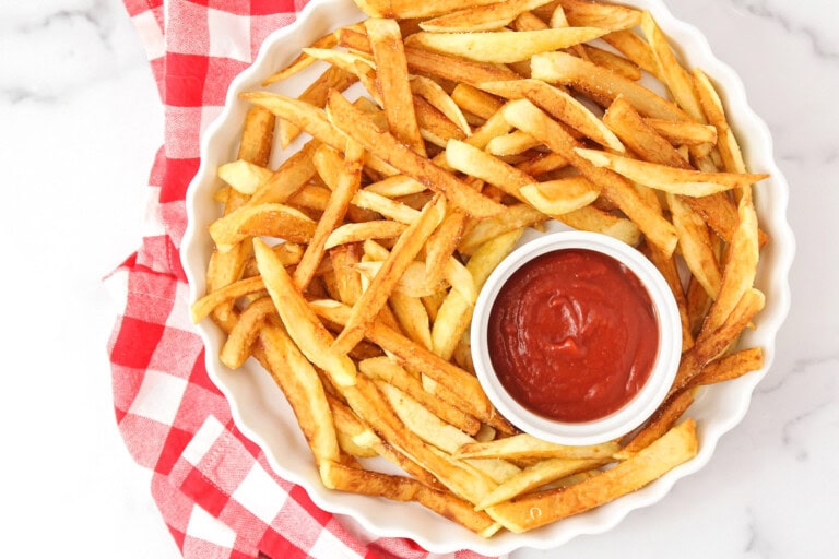 Homemade French fries in a dish with ketchup on the side.