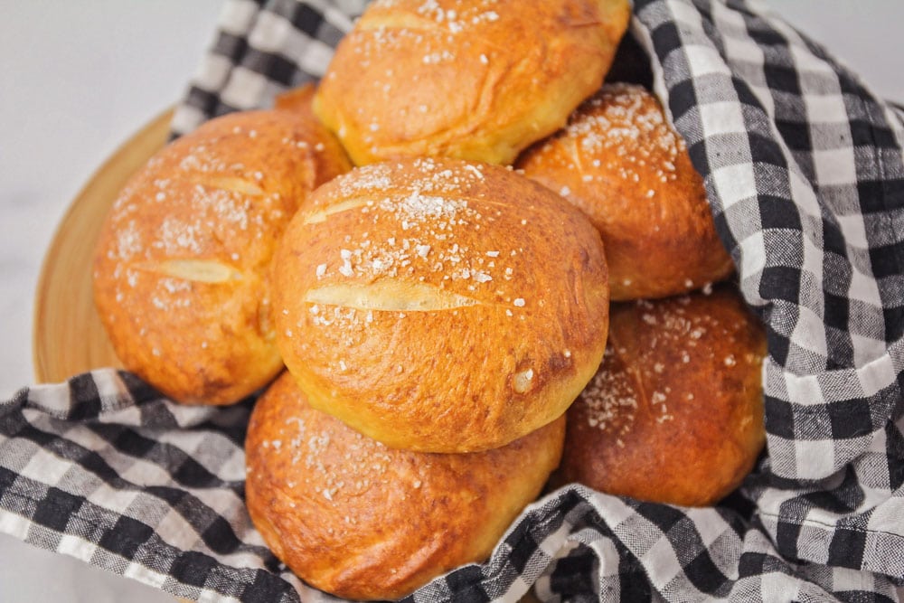 Pretzel rolls wrapped in a black and white dish towel.