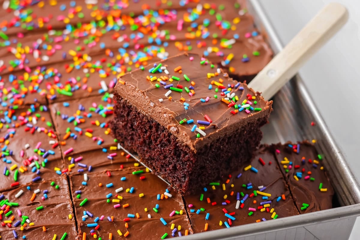 Sour cream chocolate cake piece being scooped out of baking dish.