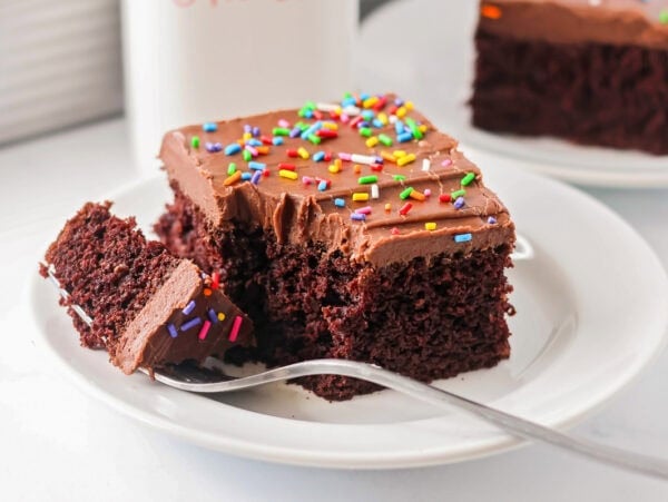 Sour cream chocolate cake recipe on white plate with fork.