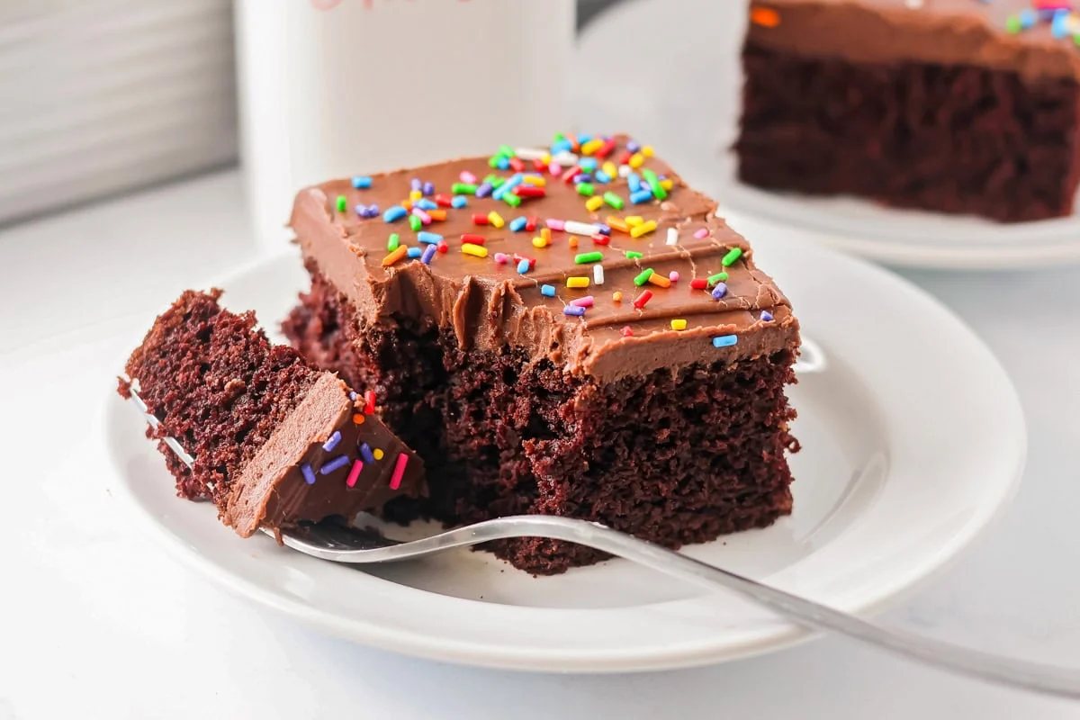 Moist sour cream chocolate cake recipe on white plate with fork.