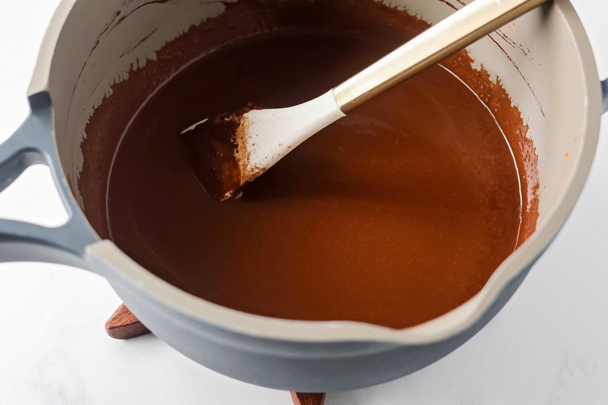 Mixing chocolate cake ingredients in pot.