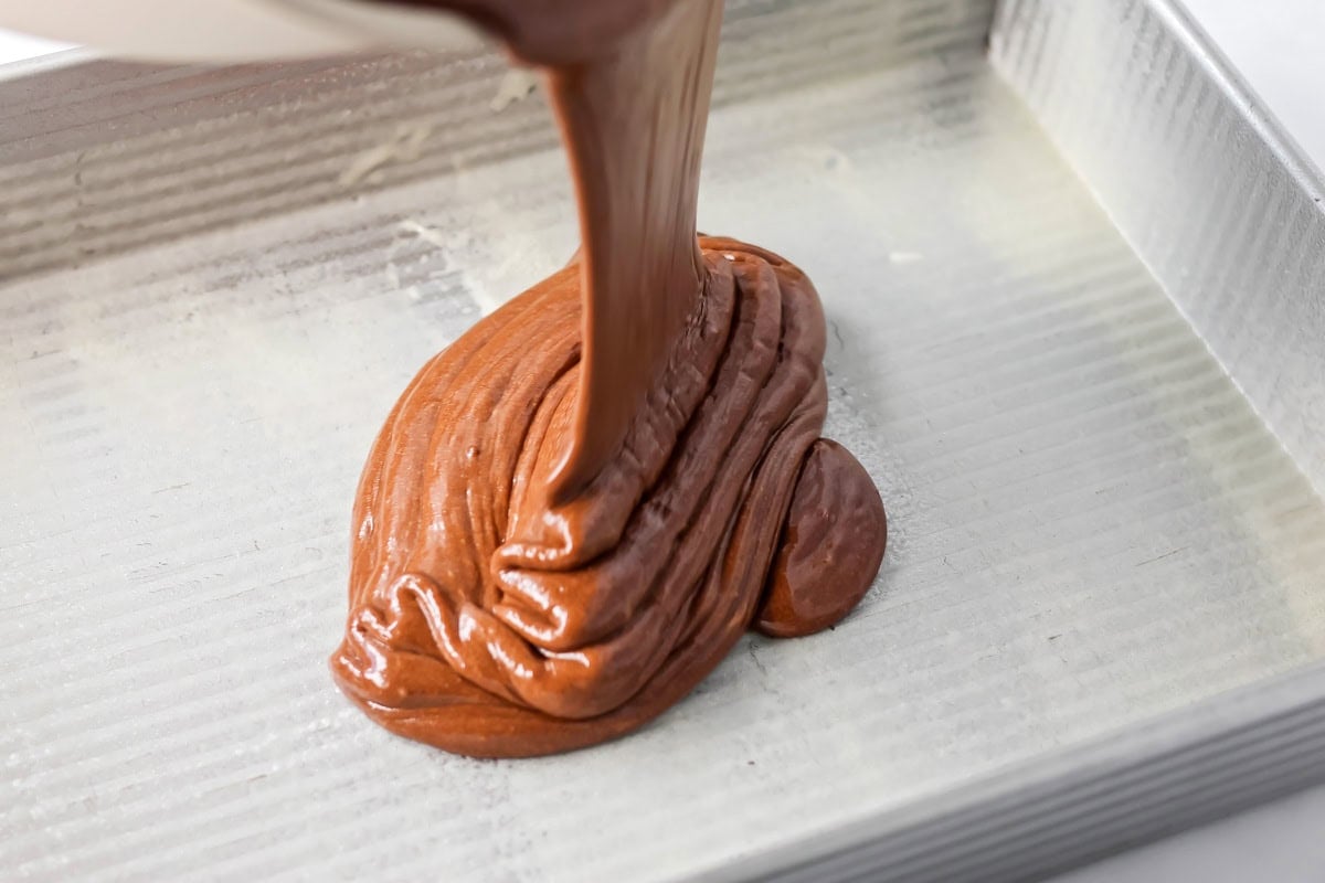 Pouring sour cream chocolate cake batter into baking dish.