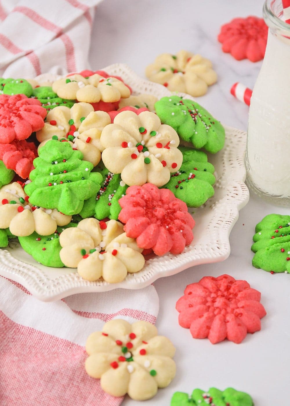 Christmas colored spritz cookies piled onto a white plate