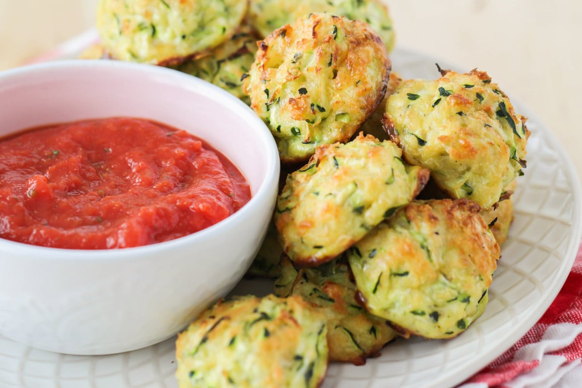 Summer Recipes - Cheesy zucchini tots on a plate with side of marinara sauce.