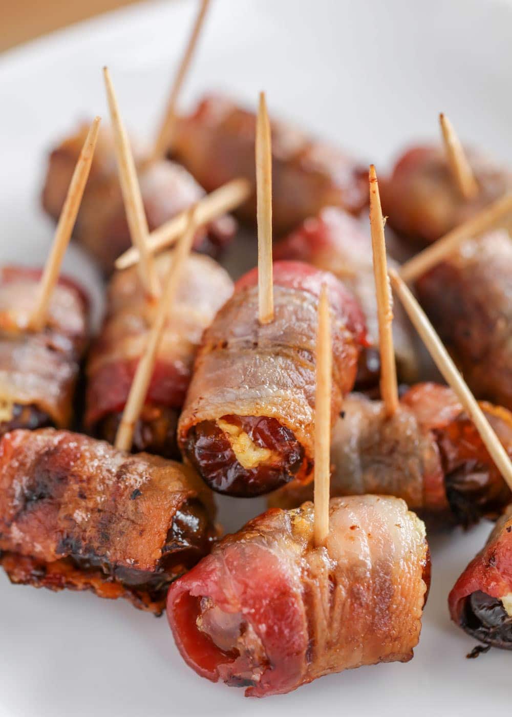 Goat cheese stuffed bacon wrapped dates on a white plate
