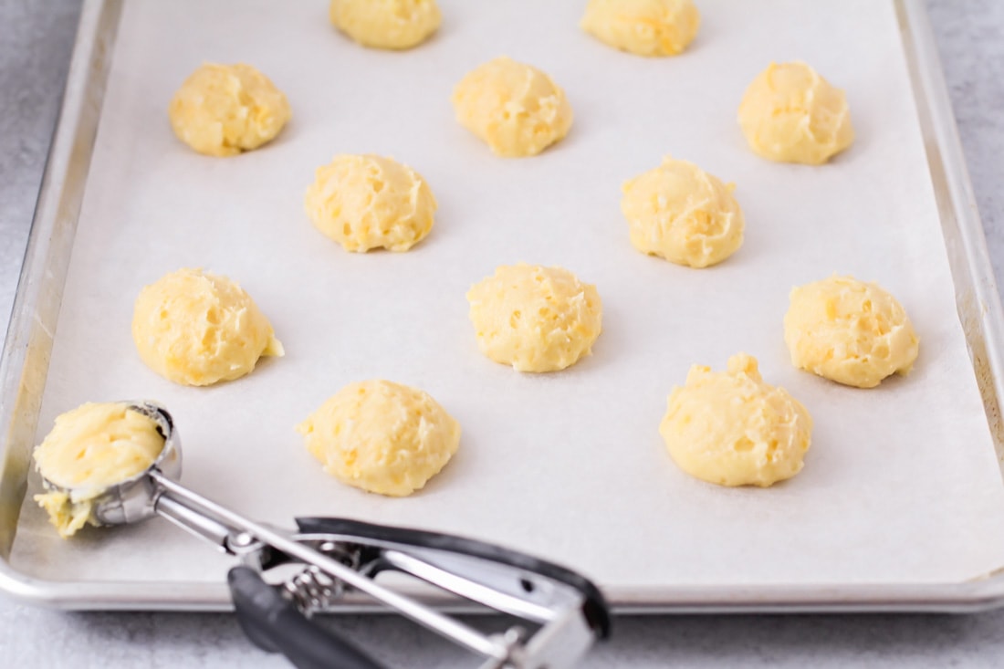 Scooping dough onto a parchment paper lined sheet pan