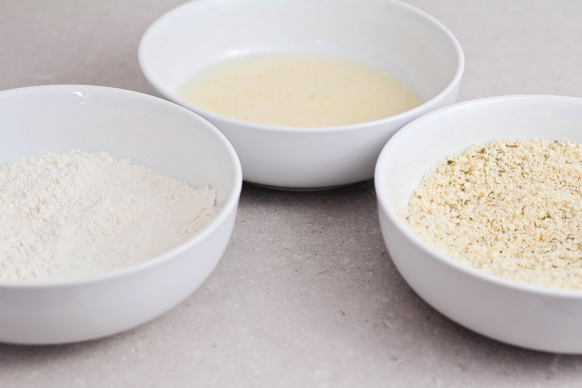 Mixing bowls with ingredients for chicken nuggets recipe.