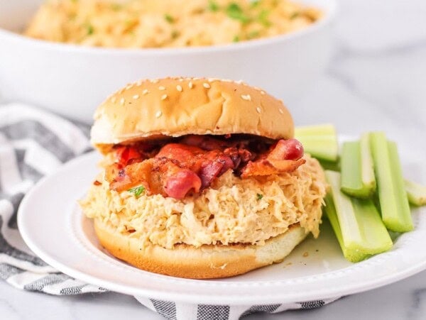 Slow Cooker Crack chicken served on a bun topped with bacon.